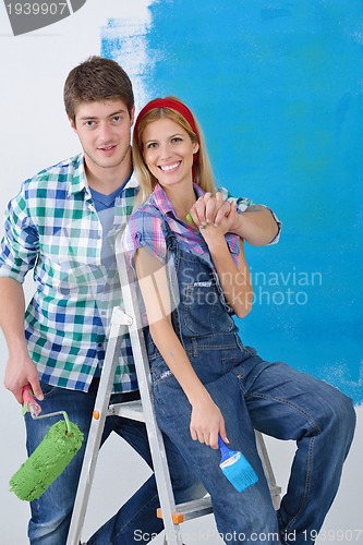 Image of happy couple paint wall at new home