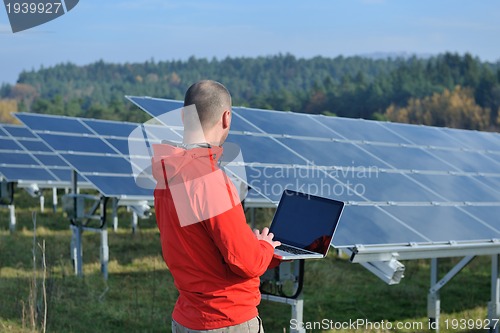 Image of engineer using laptop at solar panels plant field