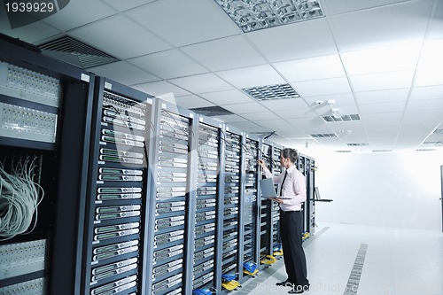 Image of businessman with laptop in network server room