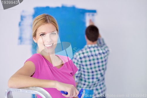 Image of happy couple paint wall at new home