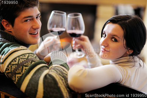 Image of Young romantic couple relax on sofa in front of fireplace at hom