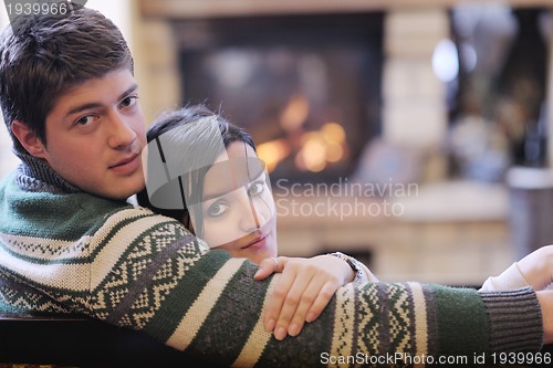 Image of Young romantic couple sitting and relaxing in front of fireplace