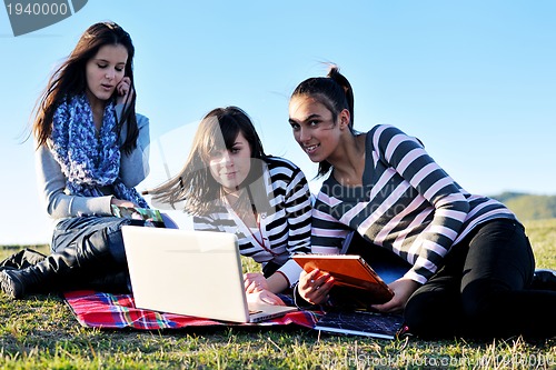 Image of group of teens working on laptop outdoor