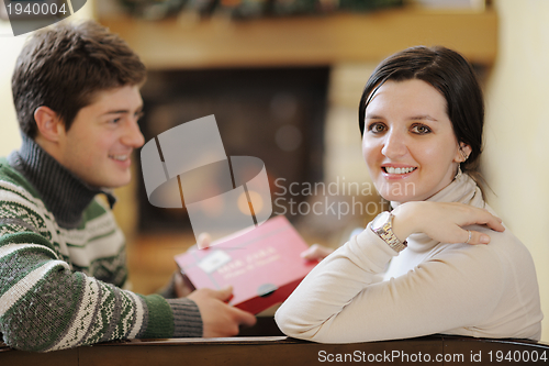 Image of Young romantic couple sitting on sofa in front of fireplace at h