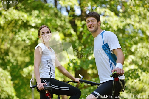 Image of Happy couple riding bicycle outdoors