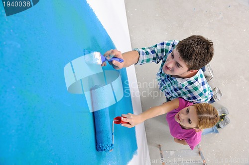 Image of happy couple paint wall at new home