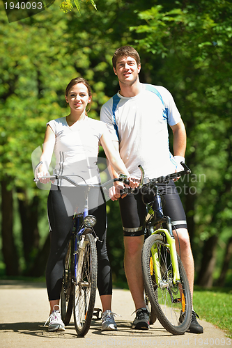 Image of Happy couple riding bicycle outdoors