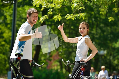 Image of Happy couple riding bicycle outdoors