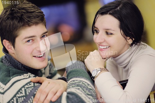 Image of Young romantic couple sitting and relaxing in front of fireplace