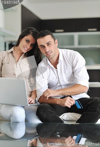 Image of joyful couple relax and work on laptop computer at modern home