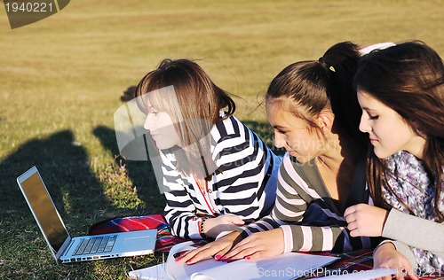Image of group of teens working on laptop outdoor