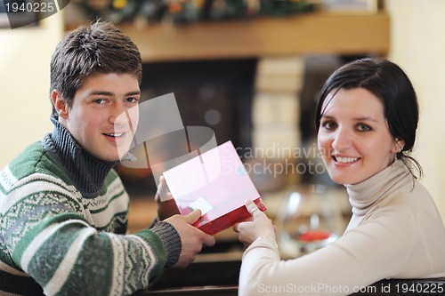 Image of Young romantic couple sitting and relaxing in front of fireplace