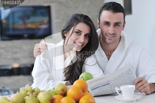 Image of Happy couple reading the newspaper in the kitchen at breakfast