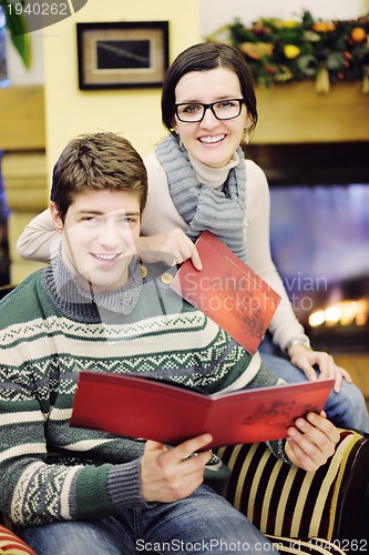Image of Young romantic couple sitting and relaxing in front of fireplace