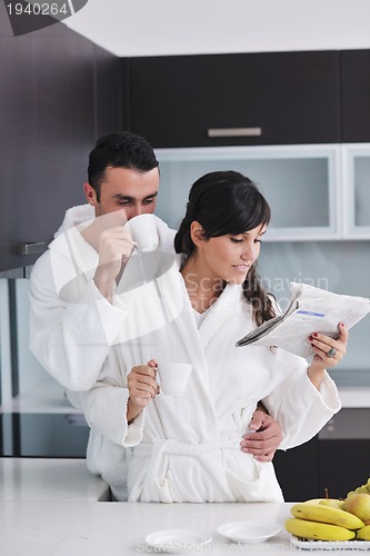 Image of Happy couple reading the newspaper in the kitchen at breakfast