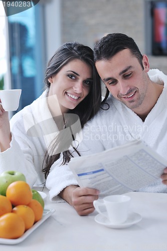Image of Happy couple reading the newspaper in the kitchen at breakfast