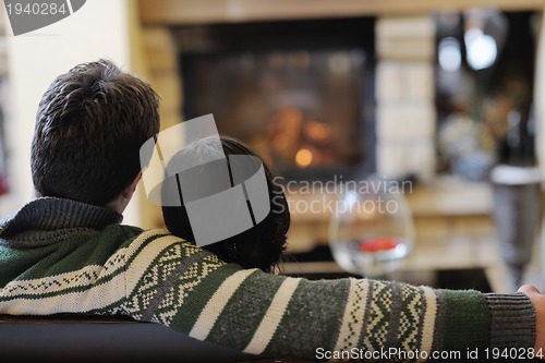 Image of Young romantic couple sitting and relaxing in front of fireplace
