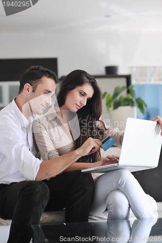 Image of joyful couple relax and work on laptop computer at modern home