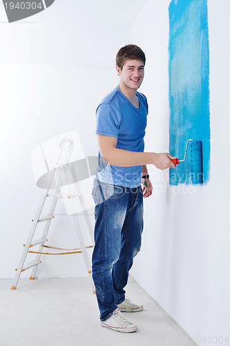 Image of handsome young man paint white wall in color