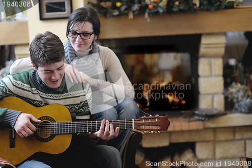 Image of Young romantic couple sitting and relaxing in front of fireplace