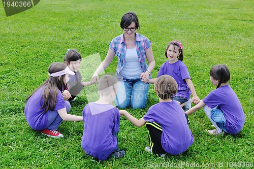 Image of happy kids group with teacher in nature