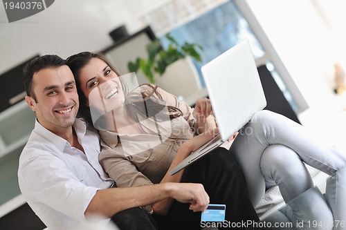 Image of joyful couple relax and work on laptop computer at modern home