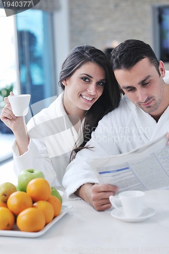 Image of Happy couple reading the newspaper in the kitchen at breakfast