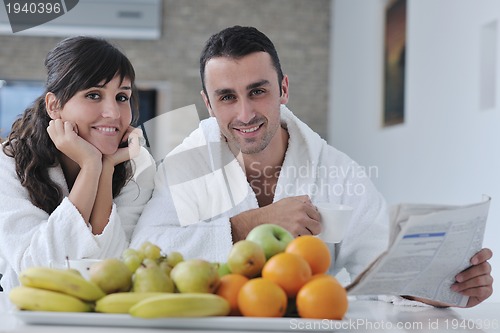 Image of Happy couple reading the newspaper in the kitchen at breakfast