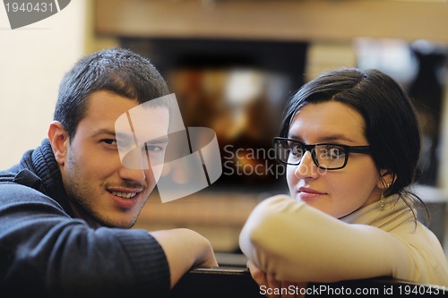Image of Young romantic couple sitting and relaxing in front of fireplace