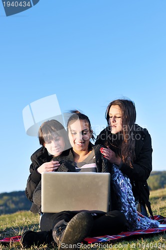 Image of group of teens working on laptop outdoor