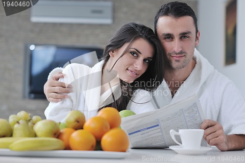 Image of Happy couple reading the newspaper in the kitchen at breakfast