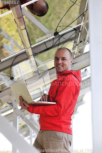 Image of engineer using laptop at solar panels plant field