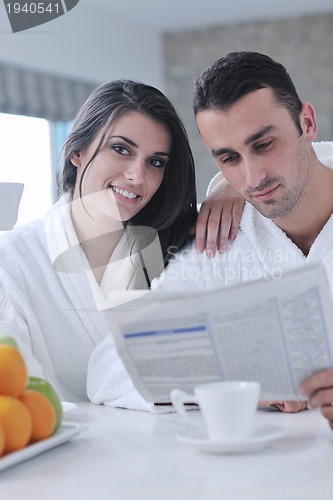 Image of Happy couple reading the newspaper in the kitchen at breakfast