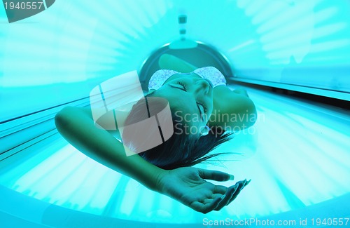 Image of Beautiful young woman tanning in solarium