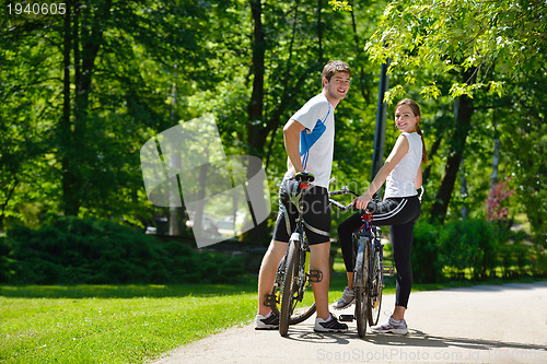 Image of Happy couple riding bicycle outdoors