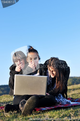 Image of group of teens working on laptop outdoor