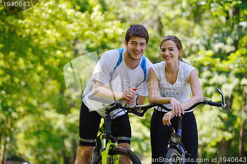 Image of Happy couple riding bicycle outdoors