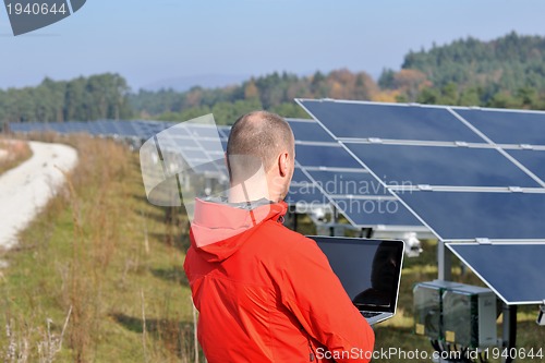 Image of engineer using laptop at solar panels plant field