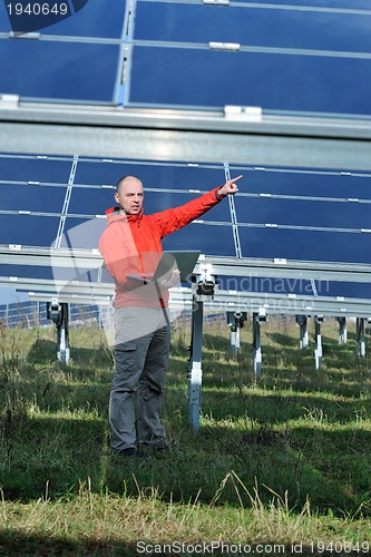 Image of engineer using laptop at solar panels plant field