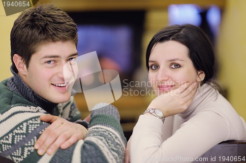 Image of Young romantic couple sitting and relaxing in front of fireplace
