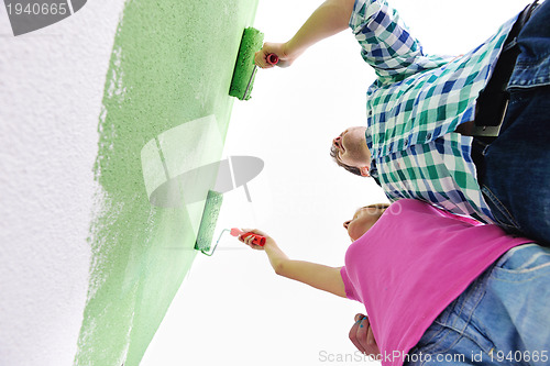 Image of happy couple paint wall at new home