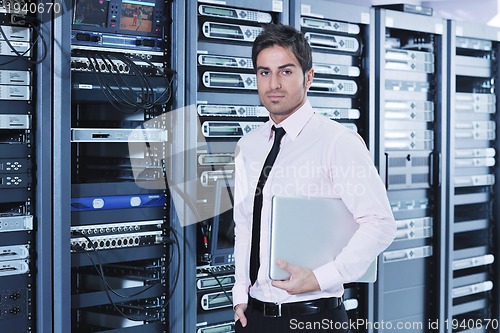 Image of businessman with laptop in network server room