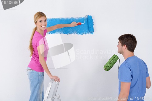 Image of happy couple paint wall at new home