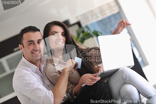 Image of joyful couple relax and work on laptop computer at modern home