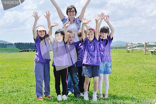 Image of happy kids group with teacher in nature