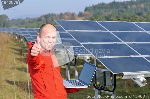 Image of engineer using laptop at solar panels plant field