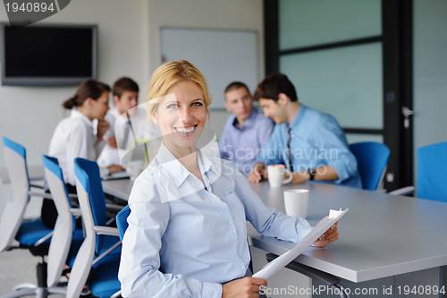 Image of business woman with her staff in background at office