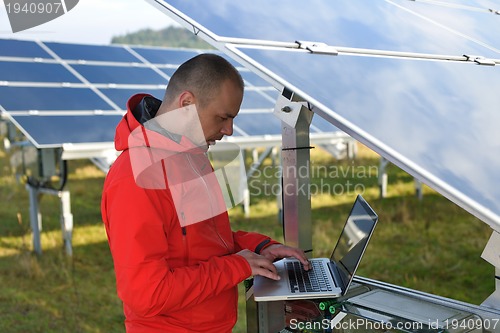 Image of engineer using laptop at solar panels plant field