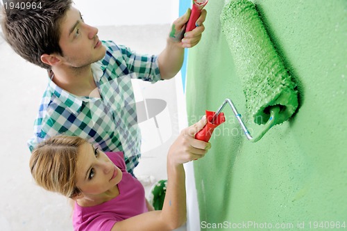 Image of happy couple paint wall at new home