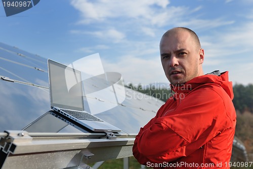 Image of engineer using laptop at solar panels plant field